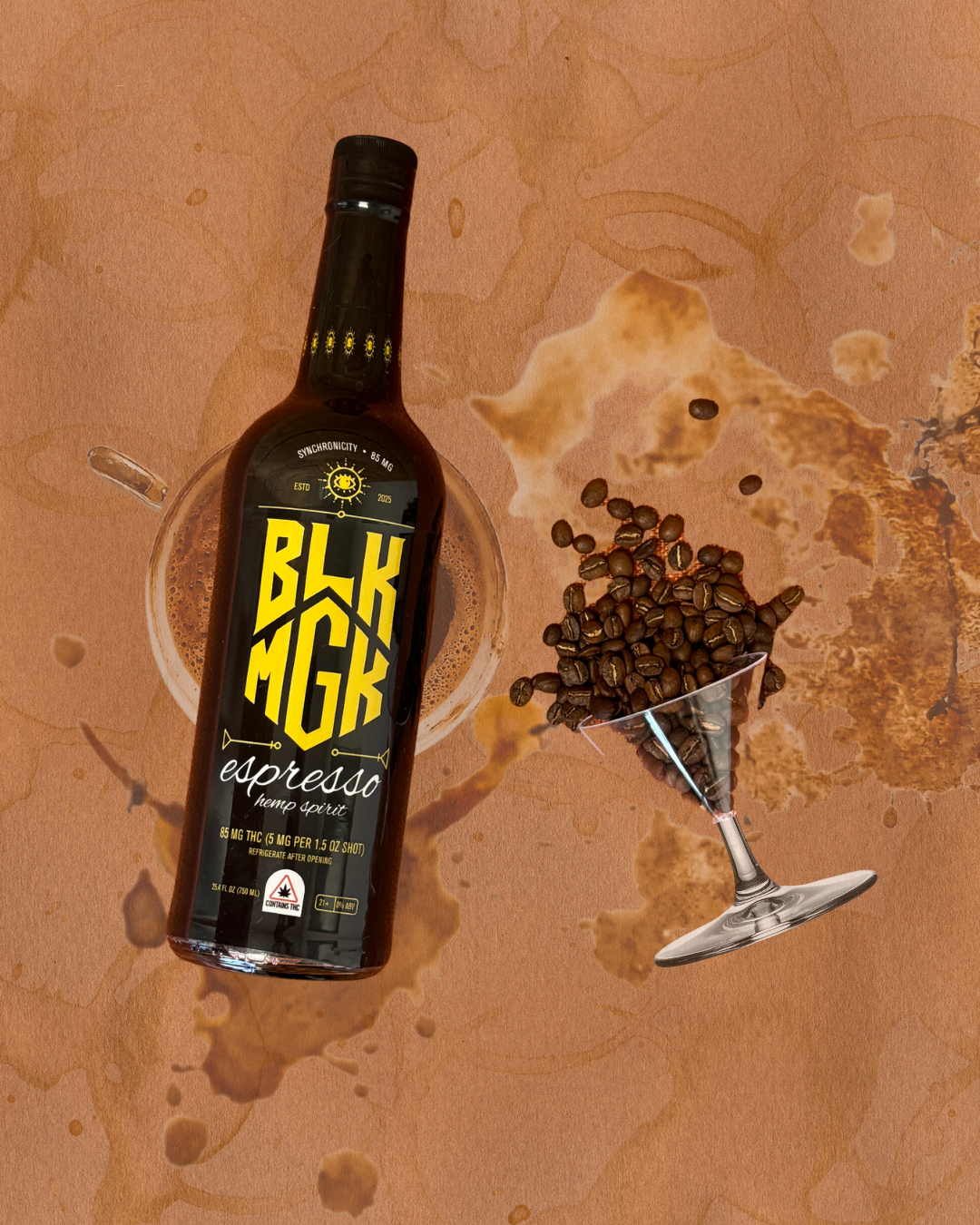 BLK MGK Espresso Hemp Spirit bottle with coffee beans spilling out of martini glass on a textured coffee stained background