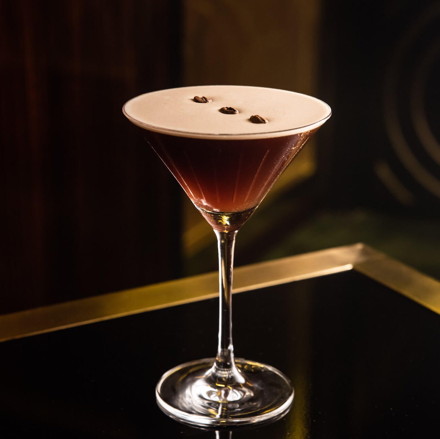 Espresso Martini cocktail with foam top in a martini glass on a dark background