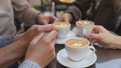 friends sitting around table at café with cappuccinos, slow zoom in on the drinks